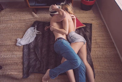 Topless couple kissing on floor