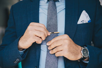 Man with pocket square adding a tie clip