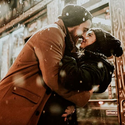 Man and woman wearing winter hats kissing