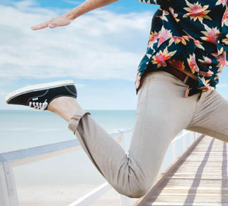 Man with rolled up pants jumping on pier