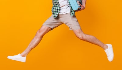 Man wearing shorts and white sneakers jumping in air 