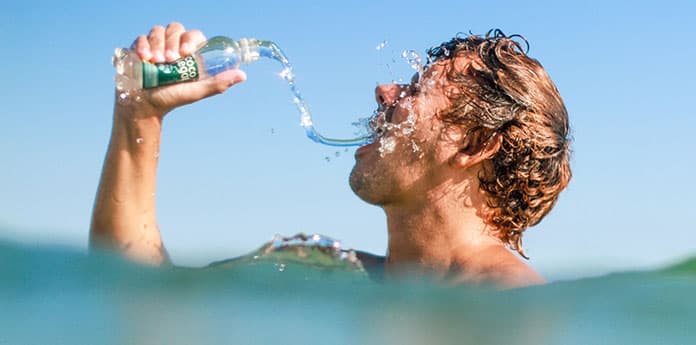 Man drinking bottle of water in ocean 