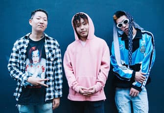 Three stylish Japanese teens pose against a blue wall