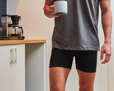 Man in boxer briefs and t-shirt holding a coffee cup