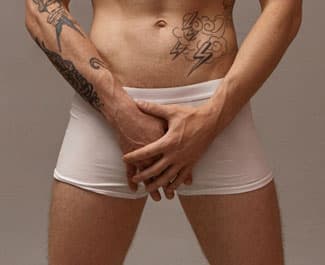 Man in white boxer briefs holding his crotch