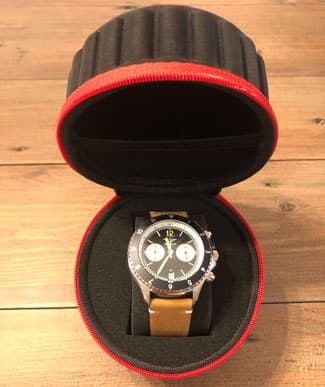 the Aeromat PNY watch in its case on a wooden table