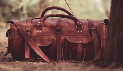 Brown leather duffle bag in the woods