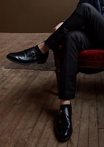 man with legs crossed wearing black monk strap shoes