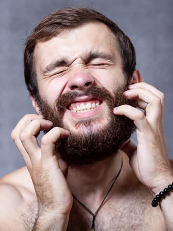 Bearded man scratching his face