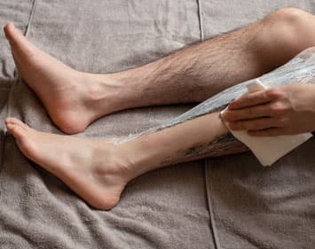 Man wiping depilatory cream from leg