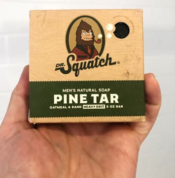 mans hand holding Dr Squatch pine tar soap