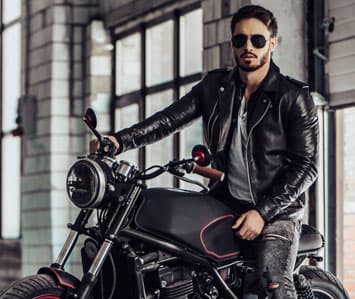 Man wearing a biker jacket sitting on a motorcycle