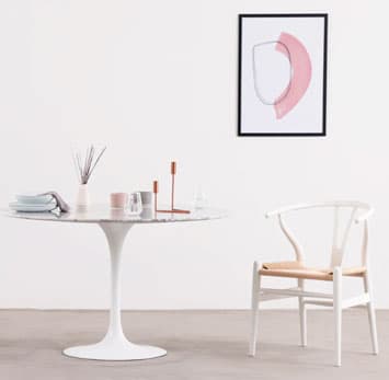 A tulip table next to a wishbone chair