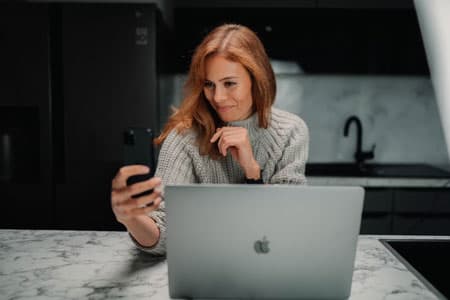 Woman using phone and computer for online dating