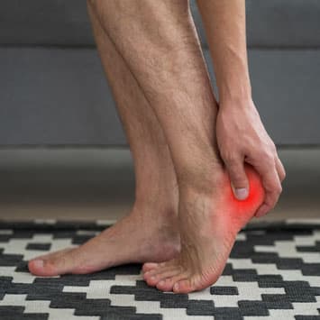 Man gripping painful heel of foot