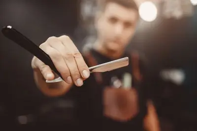 Man holding up a straight razor 