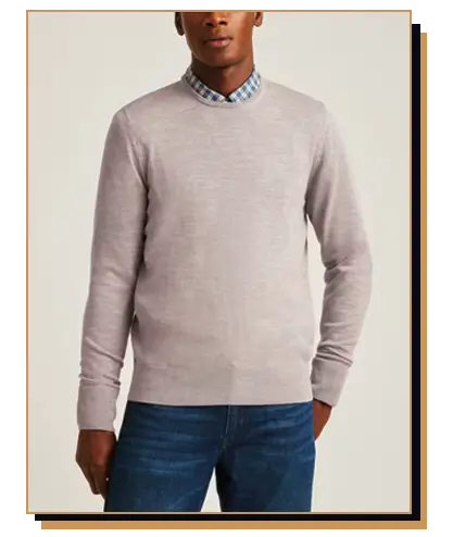 Black man wearing a grey crew neck sweater and blue jeans