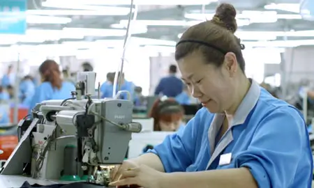 Indochino worker in China sewing a suit together