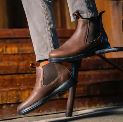 Man wearing grey jeans and brown Chelsea boots