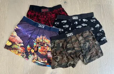 Collection of Saxx boxer briefs on a wooden floor