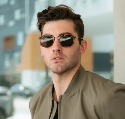 Man wearing stylish sunglasses and green bomber jacket