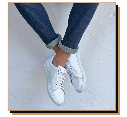 Man wearing white sneakers and slim fit dark jeans