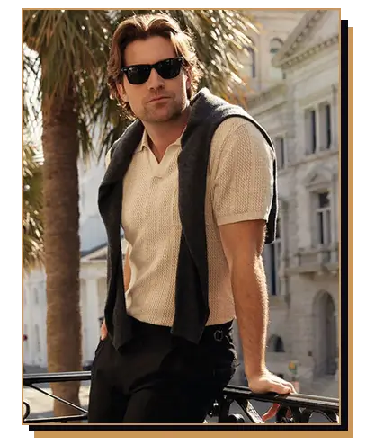 Man wearing knit polo with a sweater on his shoulders