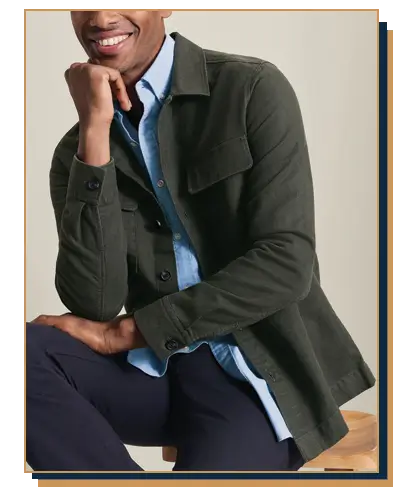 A smiling man wearing a green overshirt over a light blue button down