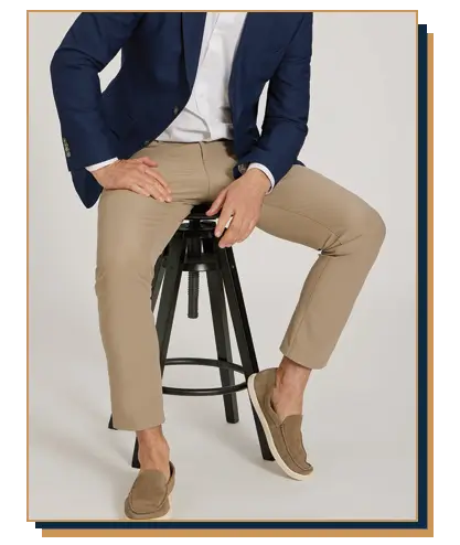 Man wearing a blue blazer and white shirt with khaki travel chinos from Mott and Bow sitting on a stool