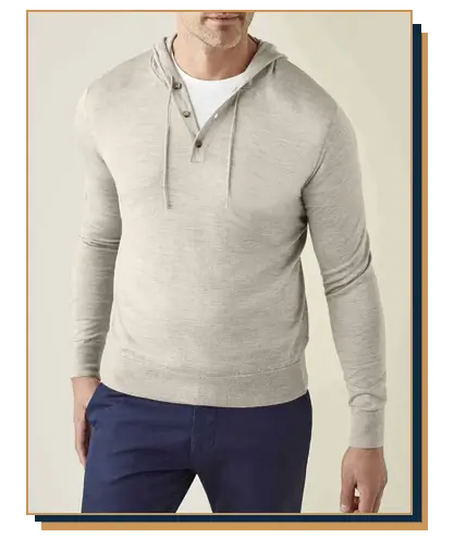 Man wearing a light beige button-placket knit hoodie layered over a white crew neck t-shirt with navy blue trousers