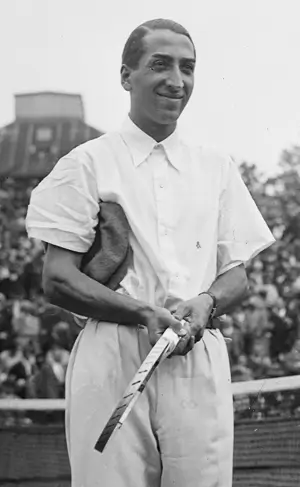 A black and white photo of Rene Lacoste holding a tennis racket in 1928